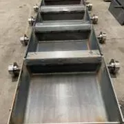 Robustes Plattenband aus Metall mit seitlichen Rollen, geeignet für Förderanlagen.