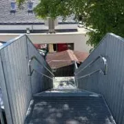 Blick von oben auf eine verzinkte Außentreppe mit Geländer und Handlauf.