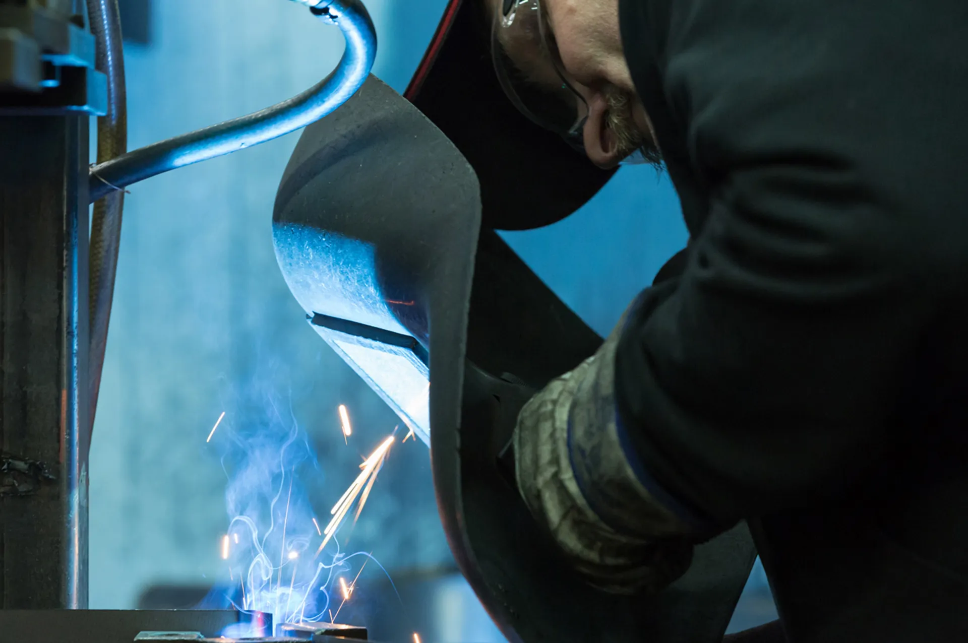 Schweißer bei präzisen Arbeiten mit Funkenflug, Fokus auf geprüfte Qualität und Sicherheit.